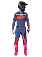 Alpinestars 2025 Techstar Dreem Ausrüstungsset, Motocross-Fahrer in voller Rennausrüstung, graublaues Trikot und Hose mit leuchtend pinken, orangefarbenen und cyanblauen Akzenten, großes 'astars' Logo auf der Brust, leuchtend pinke Stiefel, schwarzer Helm mit Goggles, koordiniertes Outfit für professionelles Motocross