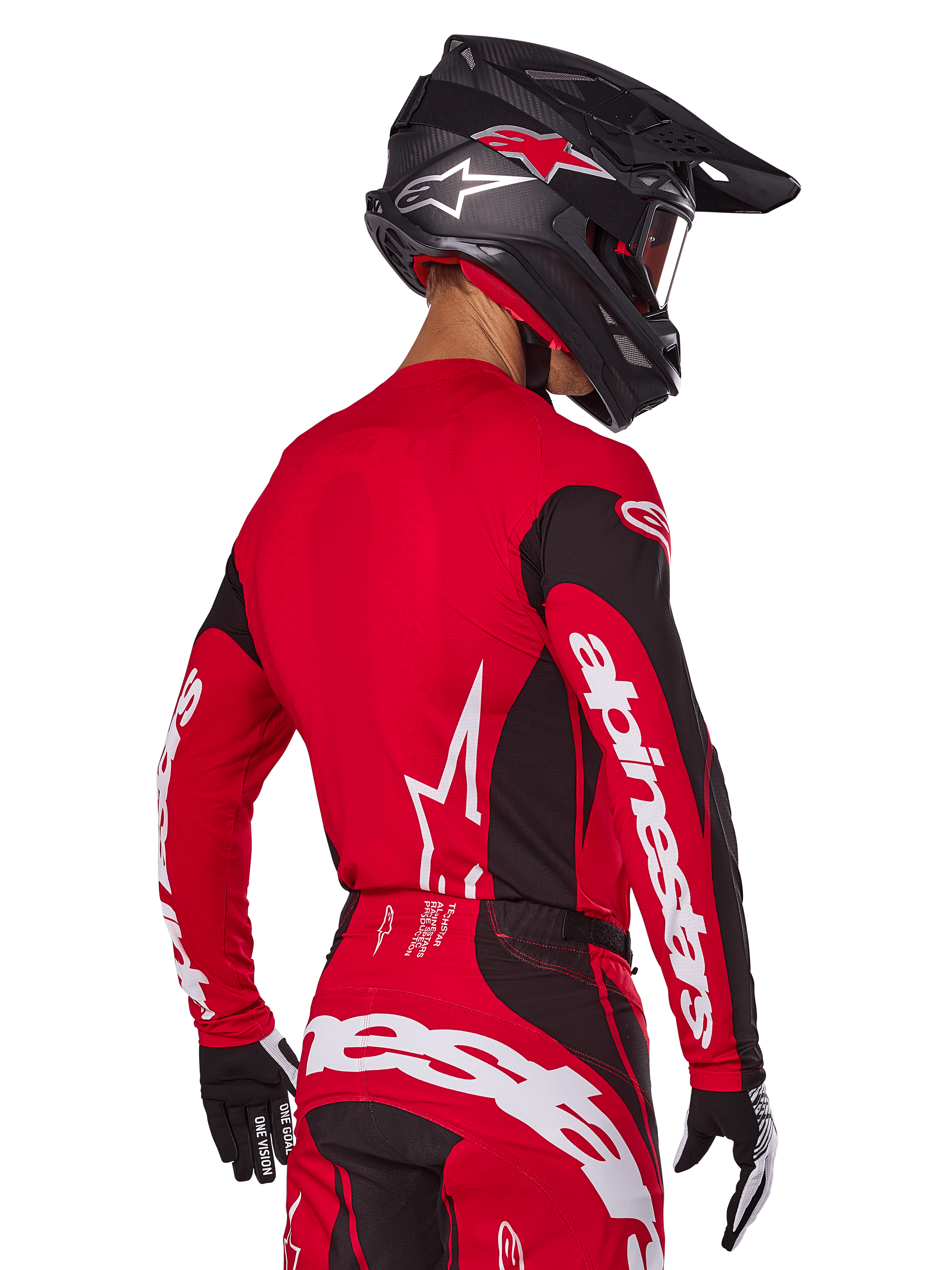 Motocross-Fahrer in der Rückansicht im Alpinestars 2025 Techstar Dreem Gear Set, rot-schwarzes Jersey mit weißem Branding an den Ärmeln, passende rot-schwarze Hose mit markantem weißem Logo auf dem Gesäß, schwarzer Carbon-Helm mit roten Akzenten, schwarz-weiße Handschuhe, professionelles Offroad-Rennoutfit.