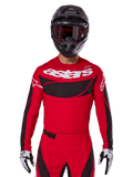 Alpinestars 2025 Techstar Dreem Trikot, Motocross-Ausrüstung, Hellrot und Schwarz, mit weißem „astars“-Logo und schwarzem, belüftetem Brustpanel, getragen mit passender Hose, schwarzem Helm und weiß-schwarzen Handschuhen, konzipiert für professionellen Offroad-Rennsport
