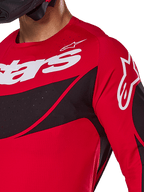 Alpinestars 2025 Techstar Dreem Trikot, Motocross-Trikot, Leuchtend Rot und Schwarz, Nahaufnahme von Brust und Schulter mit weißem Branding, schwarze diagonale Einsätze mit lasergeschnittenen Perforationen zur Belüftung, sportliche Racing-Passform für Offroad-Performance.