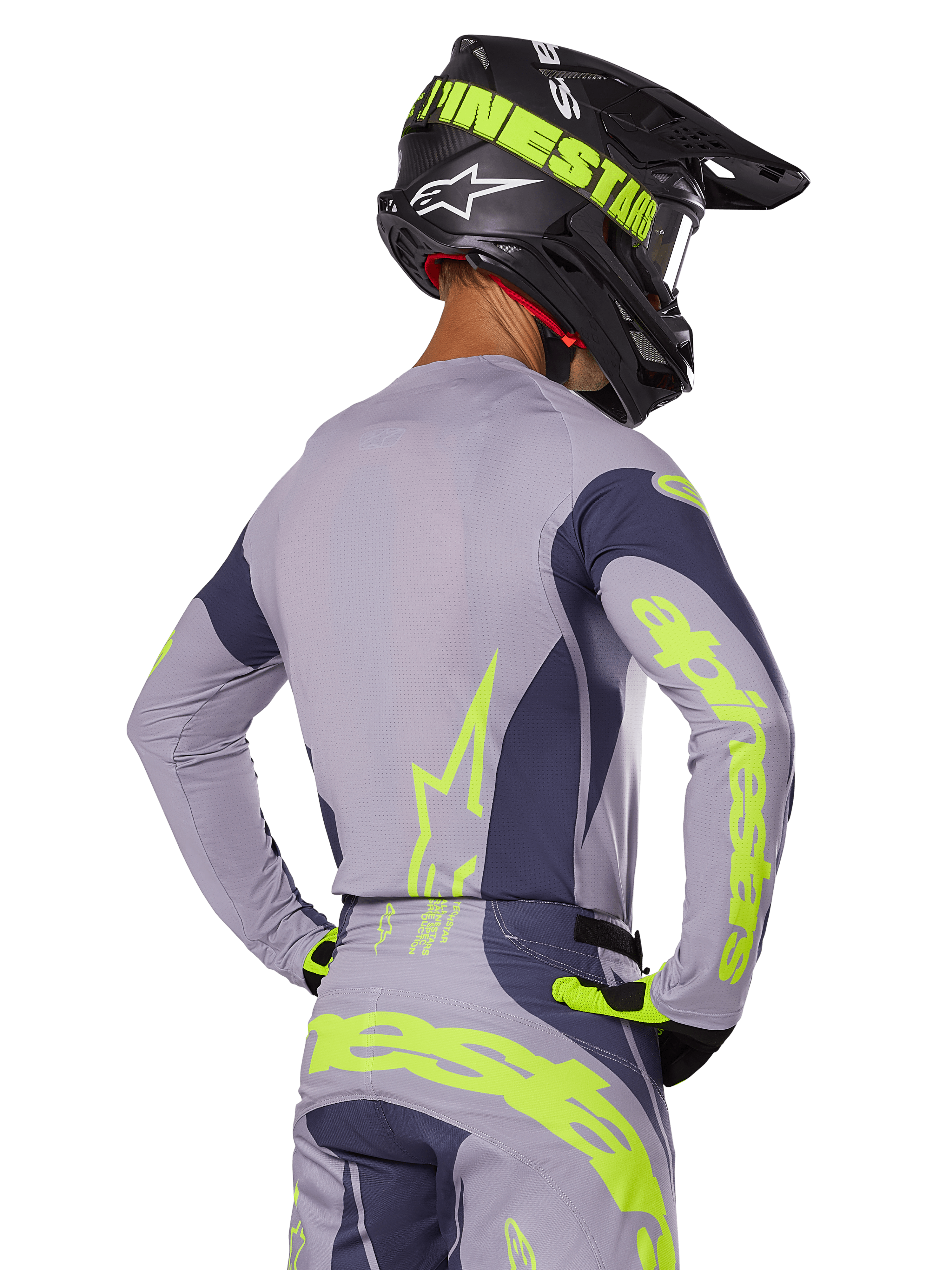 Motocross-Fahrer in der Rückansicht im Alpinestars 2025 Techstar Dreem Gear Set, graues Jersey und Hose mit leuchtend neongelbem Branding, passender schwarzer Helm mit Neon-Grafiken, professionelle Motocross-Rennausrüstung