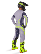 Motocross-Fahrer in der Rückansicht im Alpinestars 2025 Techstar Dreem Gear Set, Grau und Dunkelgrau mit neongelbem Branding, passendes Trikot und Hose, schwarzer Helm mit gelben Akzenten und leuchtend neongelbe Stiefel, professionell abgestimmtes Motocross-Outfit.