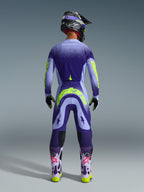Alpinestars 2026 Supertech Scenz Gear Set, Motocross-Fahrer von hinten in lila und fliederfarbener Ausrüstung mit neongelben Akzenten, Trikot und Hose mit einem Punktmuster-Farbverlauf, passender Helm und Brille, helllila Stiefel mit pinkfarbenen Logos und neongelben Sohlen, professionelle Motocross-Rennausrüstung