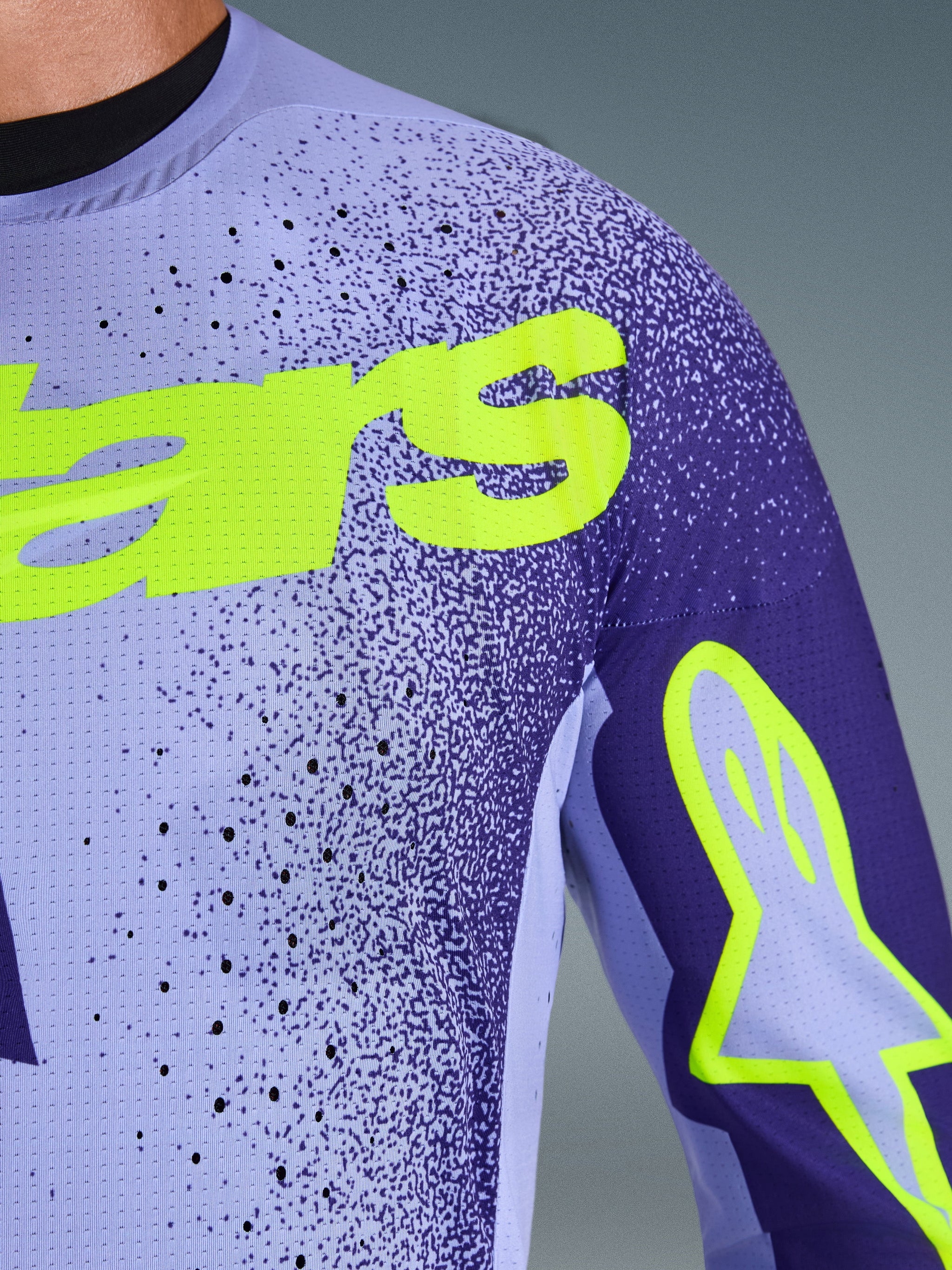 Alpinestars 2026 Supertech Scenz Jersey, motocross shirt, paars en fluogeel, detailopname van het geperforeerde stretch-mesh materiaal en de felgele Alpinestars-branding op de borst en mouw