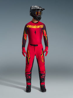 Alpinestars 2026 Supertech Scenz Gear Set, complete motocross racing outfit in red and black with yellow graphics, featuring a pro-level jersey and matching pants, worn with a black helmet, red gloves, and black racing boots, premium performance gear for off-road competition