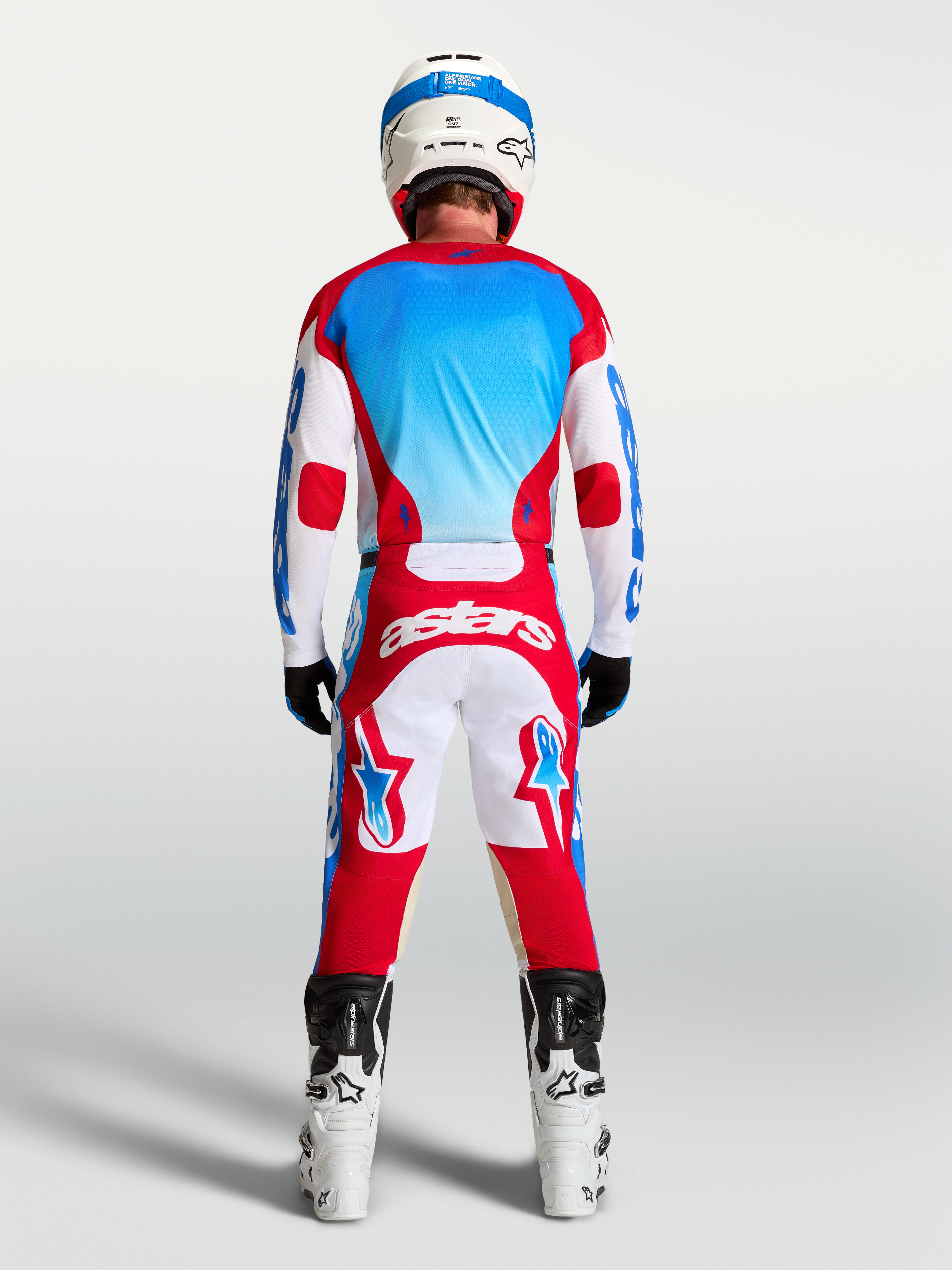 Alpinestars Racer Hunt broek en gear set, rood, wit en blauw, achteraanzicht op model in motocrossuitrusting.