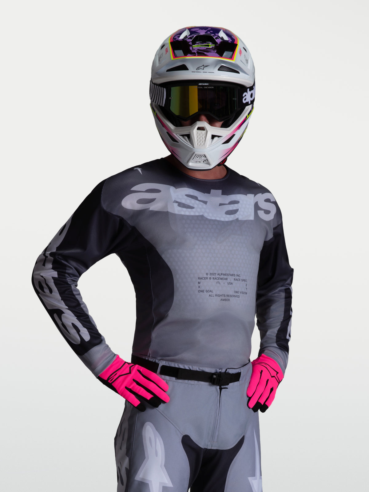 Alpinestars Maillot Racer Amber, maillot de motocross performant pour homme, gris et noir, panneaux en mesh respirant, porté par un pilote avec casque et gants, équipement de protection tout-terrain