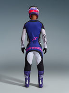 Rückansicht eines Motocross-Fahrers, der das Alpinestars 2026 Techstar Knif Jersey in Schwarz, Hellgrau und Lila trägt, mit weißen Ärmeln und einem pinkfarbenen Logo auf dem unteren Rücken. Kombiniert mit einer passenden Motocross-Hose, lila Stiefeln und einem farbenfrohen Helm in einem Studio-Setting.