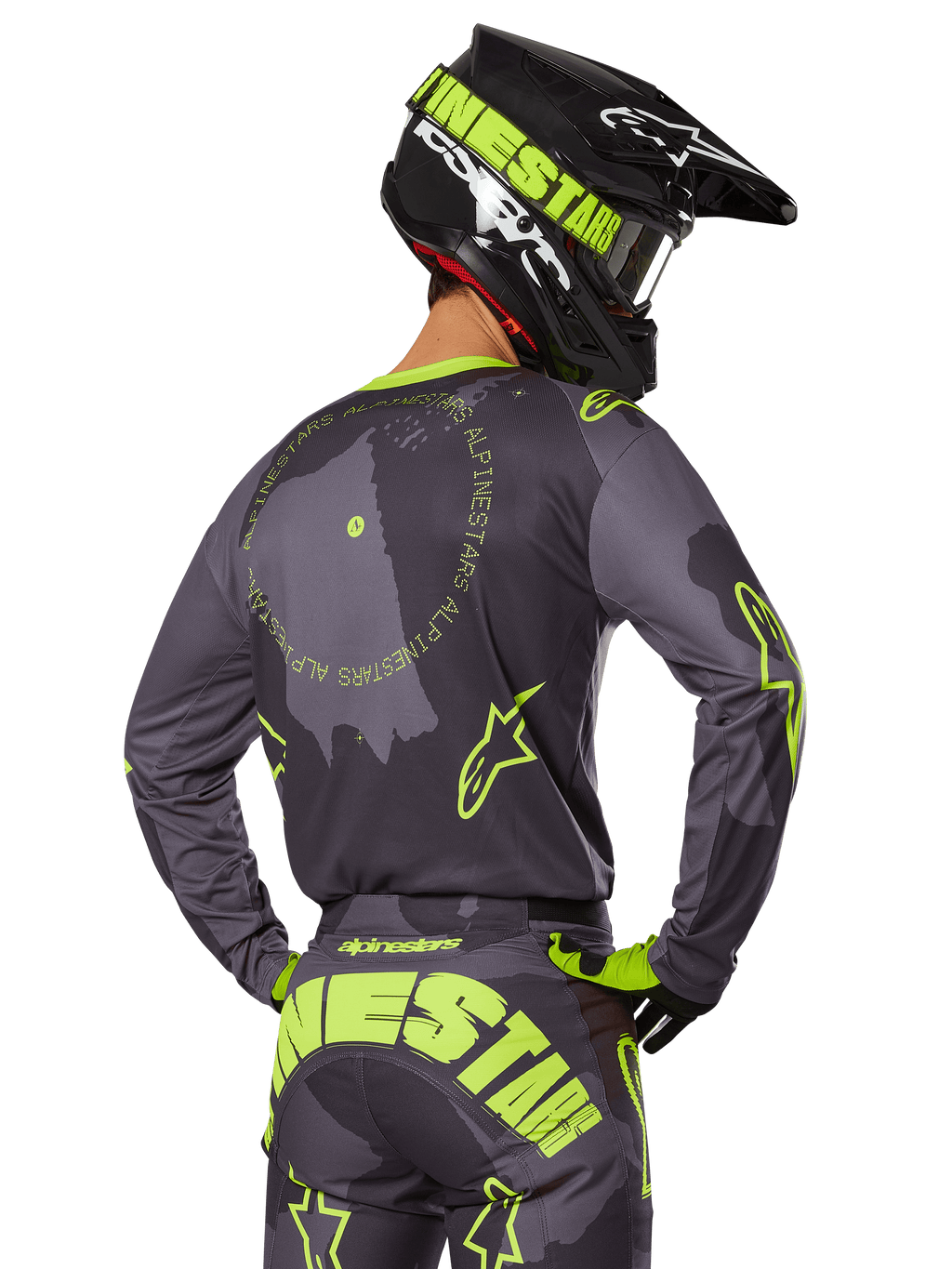 Motorcrossrijder van achteren gezien in de 2025 Racer Hollow Gear Set, grijze jersey met fluorescerend gele cirkelvormige tekst en sterlogo's, bijpassende grijze en gele broek met opvallende branding op het zitvlak, zwarte en limoengroene helm, gecoördineerde outfit voor off-road racen