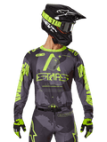 Maillot Alpinestars 2025 Racer Hollow, maillot de motocross, camouflage sombre et jaune fluo, porté avec pantalon assorti, casque noir et jaune avec masque et gants noirs, avec logo Alpinestars et motif camouflage