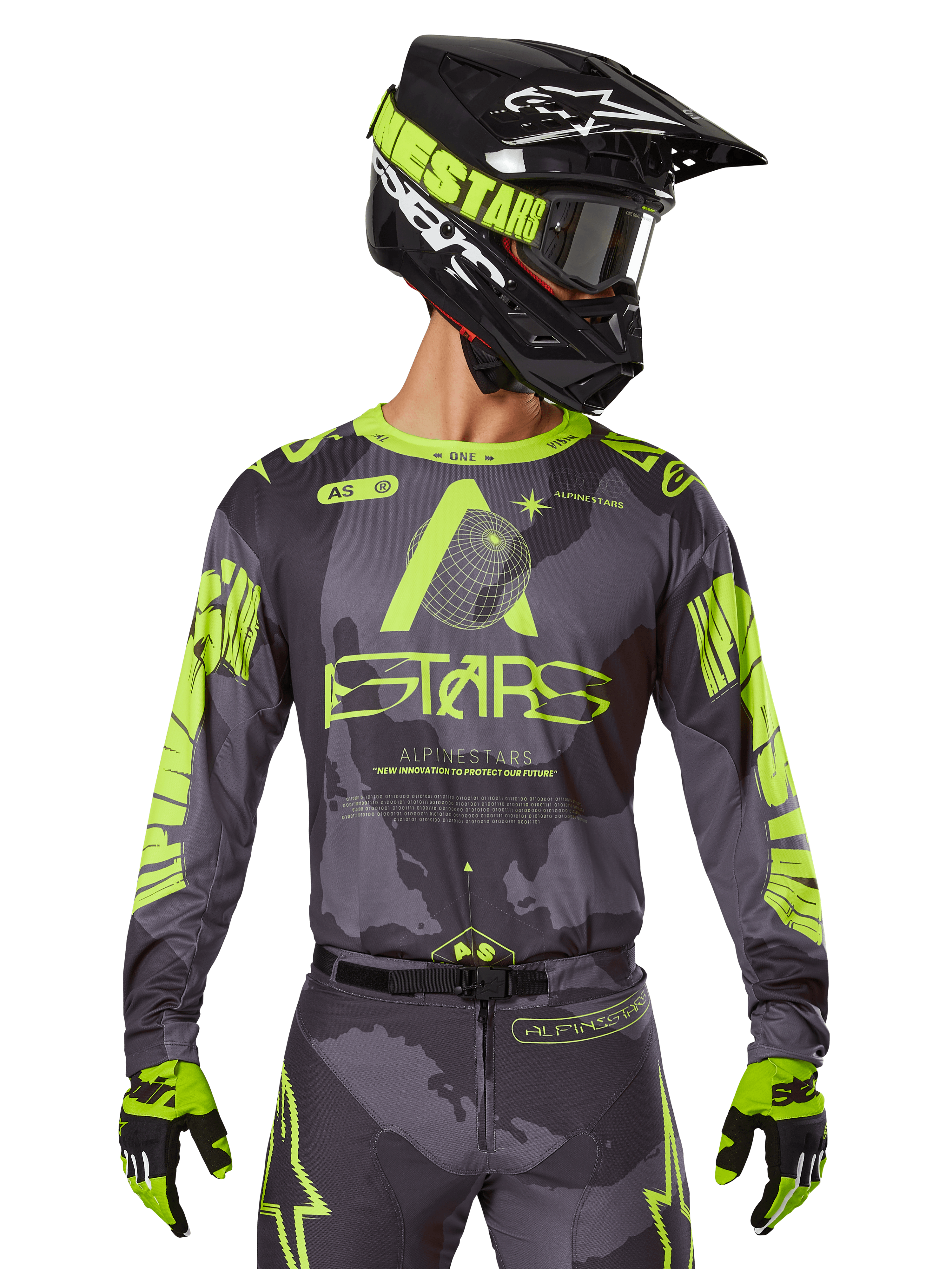 Alpinestars 2025 Racer Hollow Jersey, motorcross raceshirt, donkere camouflage en neongeel, gedragen met bijpassende broek, zwarte en gele helm met crossbril en zwarte handschoenen, voorzien van Alpinestars-branding en camouflage-ontwerp