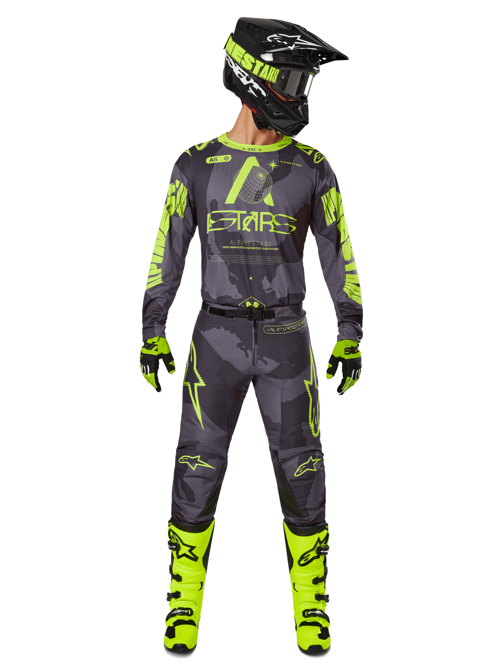 Pilote de motocross portant un équipement de course complet, maillot Alpinestars Racer Hollow 2025 et pantalon assorti en Dark Camo Yellow Fluo, avec des graphismes jaune fluo éclatants sur un fond camouflage gris foncé, gants assortis, bottes jaune fluo et casque noir.