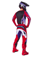 Motorcrosser van achteren gezien in de Alpinestars 2025 Fluid Wurx Gear Set, Purple Bright Red jersey met zwart rugpaneel, bijpassende crossbroek met witte en paarse accenten, felrode laarzen en zwarte helm, professionele off-road race-outfit