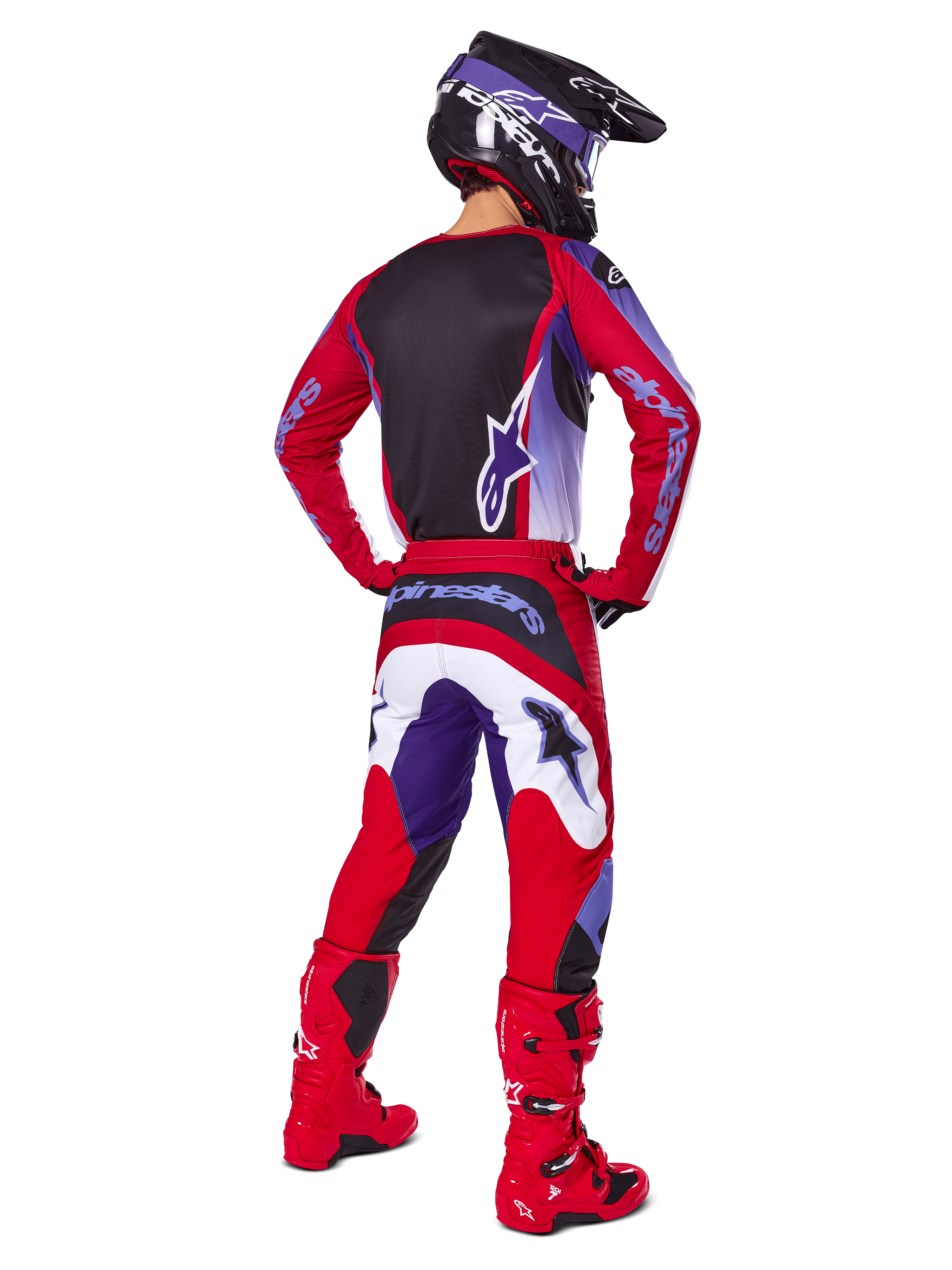 Motorcrosser van achteren gezien in de Alpinestars 2025 Fluid Wurx Gear Set, Purple Bright Red jersey met zwart rugpaneel, bijpassende crossbroek met witte en paarse accenten, felrode laarzen en zwarte helm, professionele off-road race-outfit