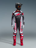 Motocross rider wearing the 2026 Techstar Nomur Gear Set, Black White and Red, jersey featuring a large red star logo and speckled pattern, matching pants with red side panels, black helmet with tinted goggles, and red motocross boots.