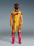 Alpinestars 2026 Techstar Nomur Gear Set, komplette Motocross-Rennausrüstung an einem Fahrer, Trikot mit gelb-orangem Farbverlauf und pinkem Stern-Logo, passende Hose und Handschuhe, leuchtend pinke Stiefel und schwarzer Helm, professionelles MX-Kit auf grauem Hintergrund