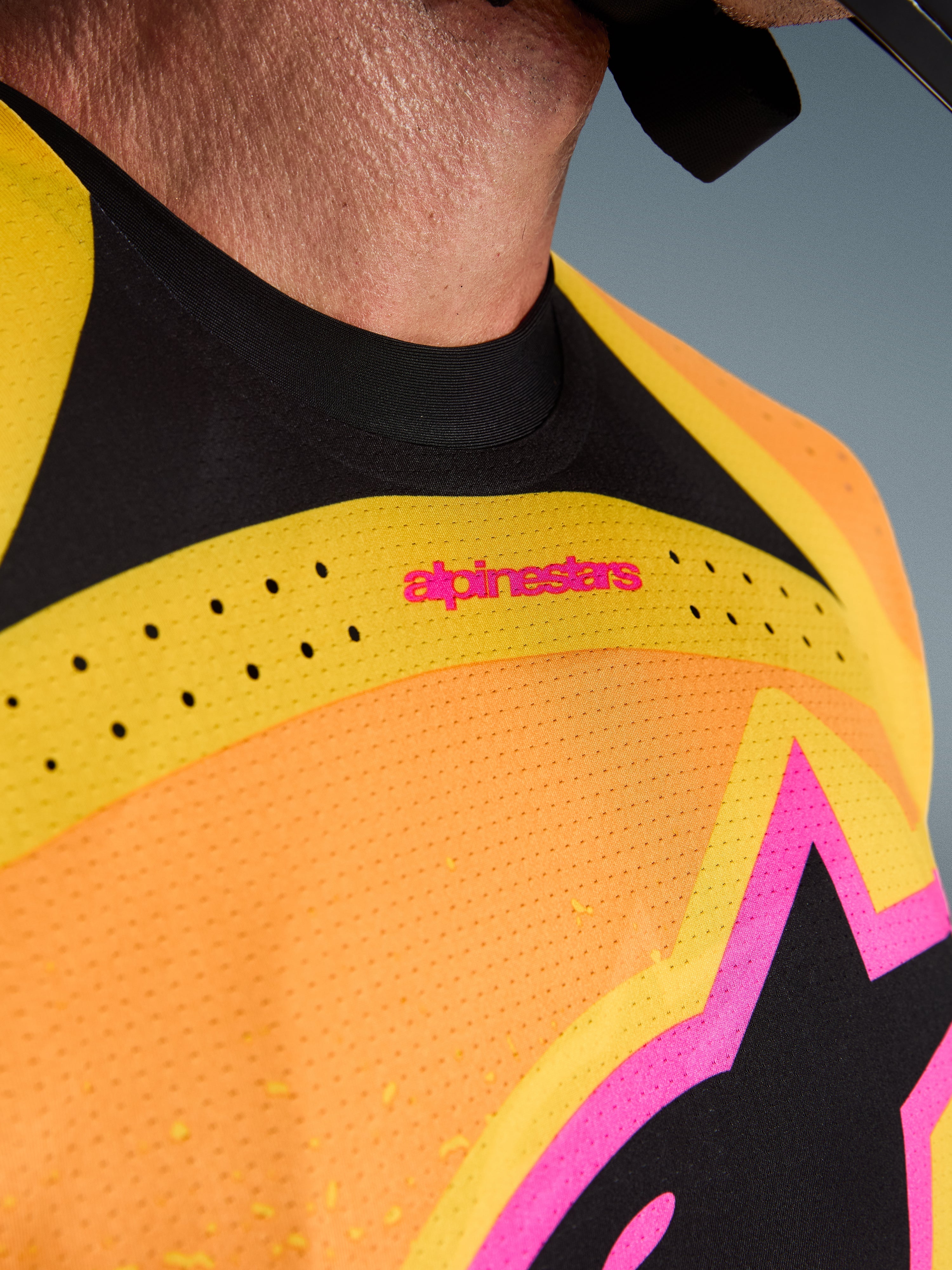 Alpinestars 2026 Techstar Nomur Trikot, Motocross-Trikot, Orange Gelb Pink, Nahaufnahme von Brust und Kragen mit lasergeschnittener Belüftung, pinkfarbenem Branding und atmungsaktivem Mesh-Gewebe