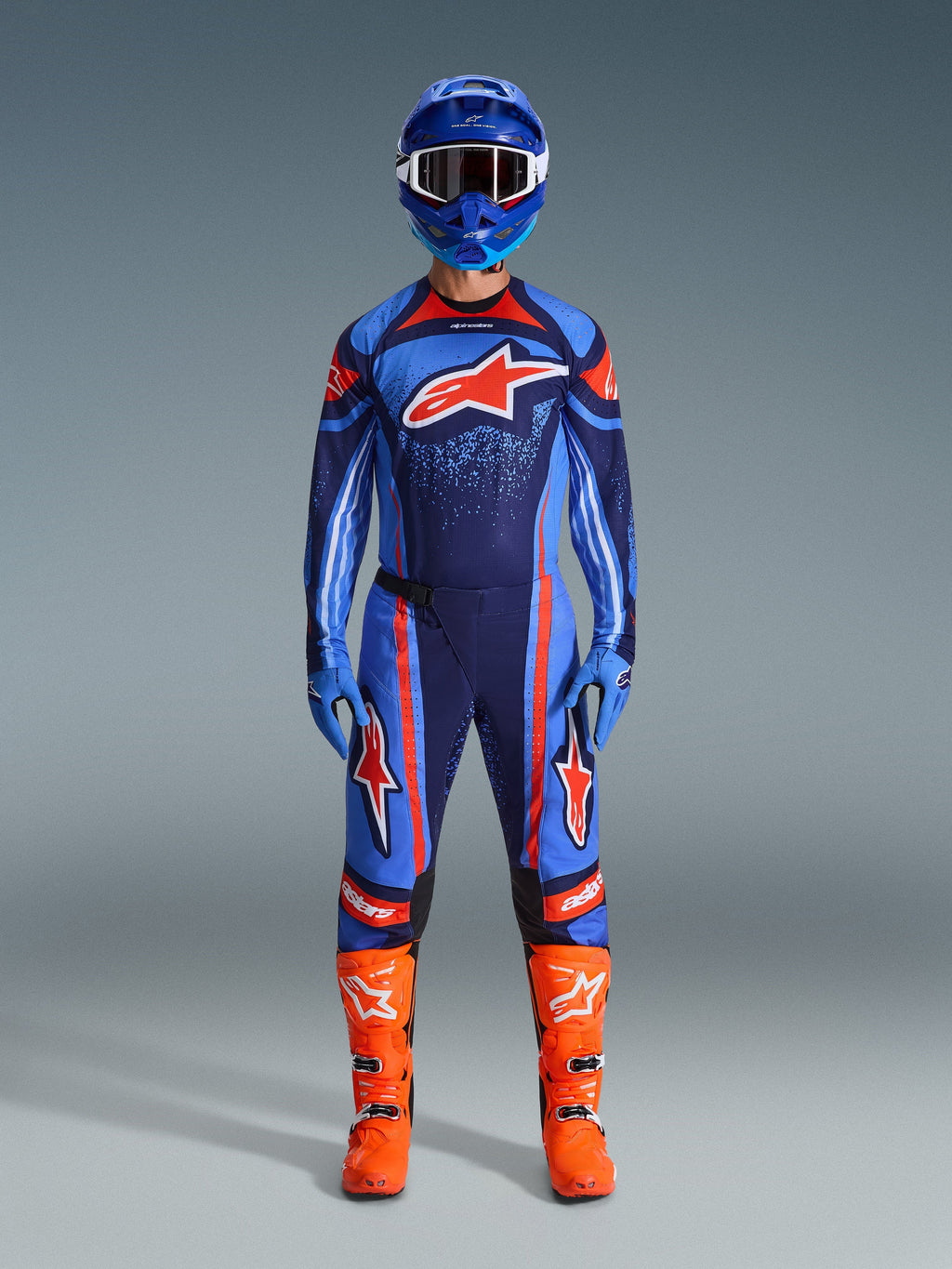Set d'équipement Alpinestars Techstar Nomur 2026, équipement de motocross, bleu marine, orange et bleu UCLA, tenue de pilotage complète avec casque bleu, maillot et pantalon assortis, gants bleus et bottes orange vif, logos étoile, protection tout-terrain haute performance