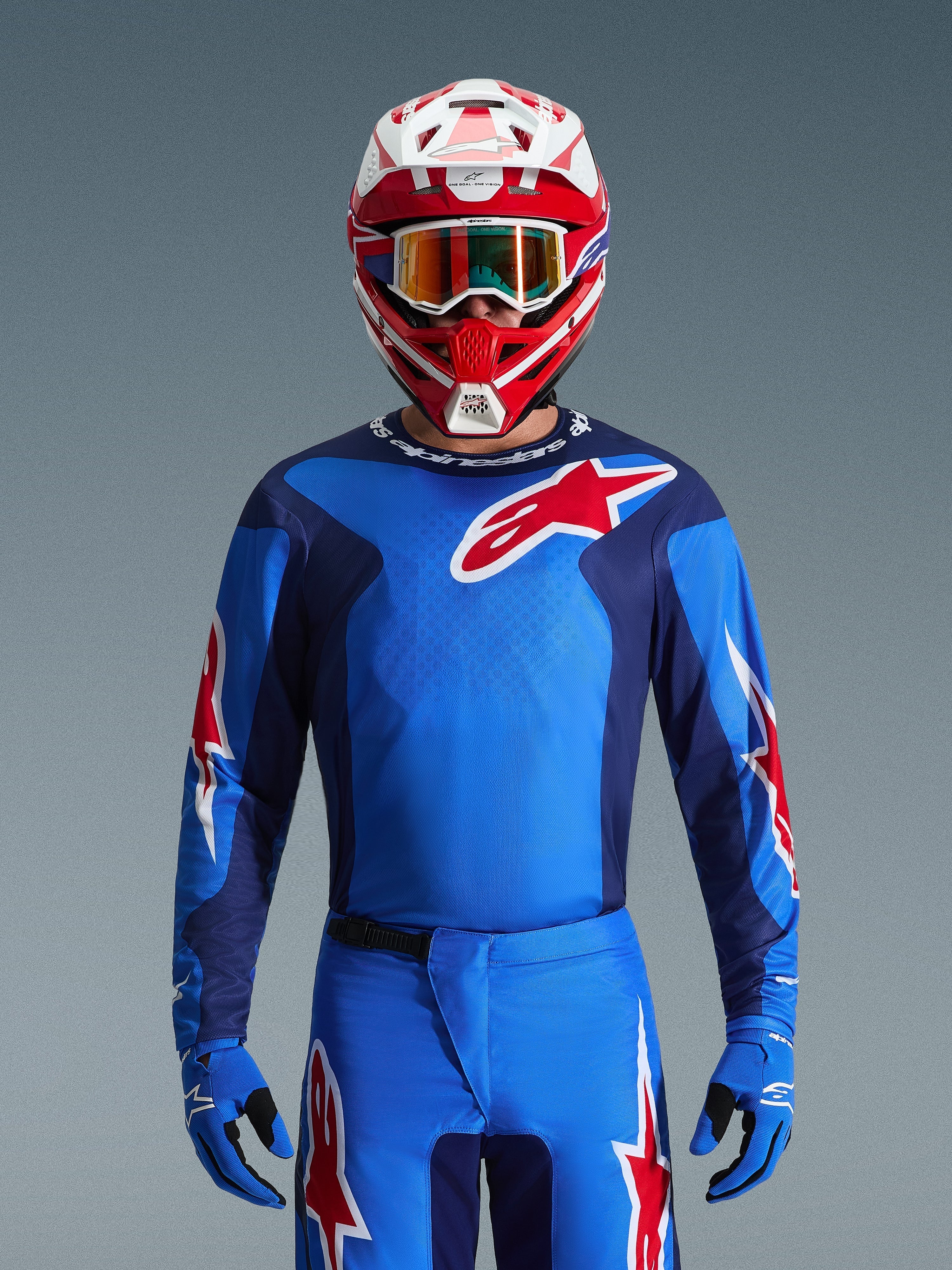 Maillot Alpinestars 2026 Fluid Grid, maillot de motocross bleu et rouge, porté avec un pantalon assorti et un casque rouge et blanc, arborant des logos à étoile rouge proéminents et une coupe athlétique conçue pour la performance tout-terrain