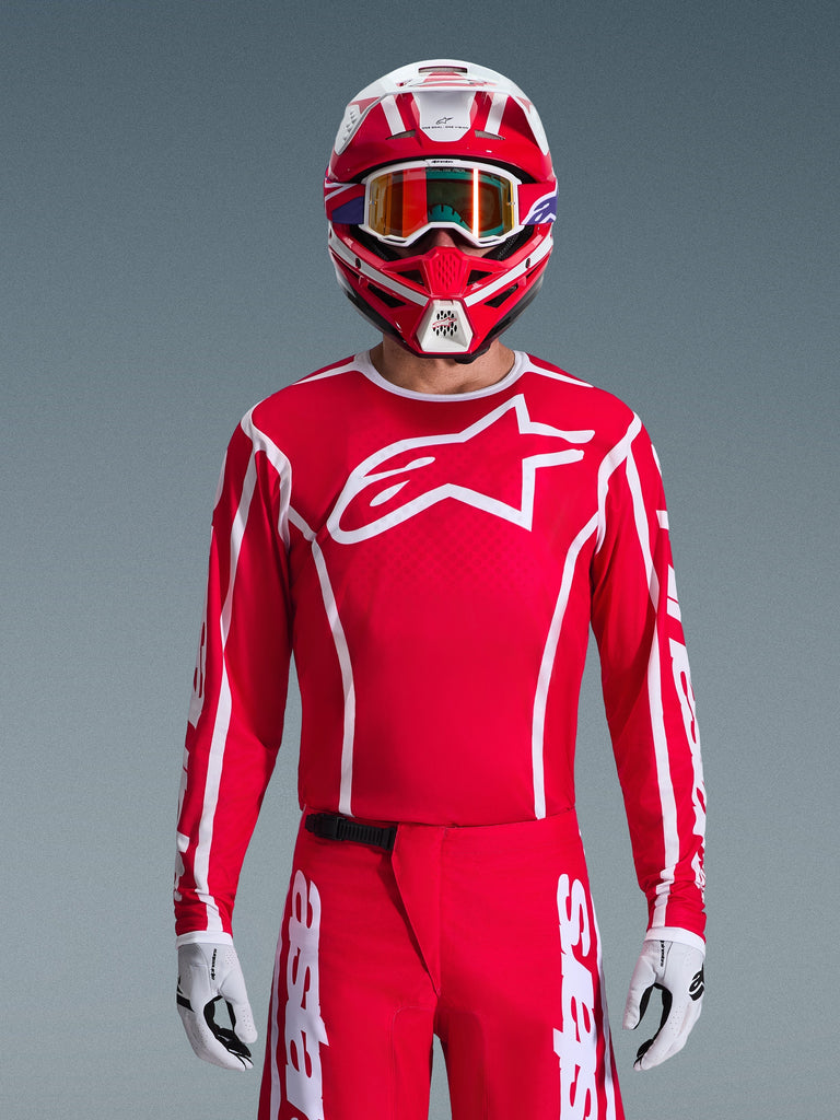 Alpinestars 2026 Fluid Apex Jersey, Motocross Jersey, Red and White, worn by a rider with a matching red and white helmet and orange goggles, featuring a prominent white logo on the chest, athletic fit, part of a coordinated off-road racing gear set