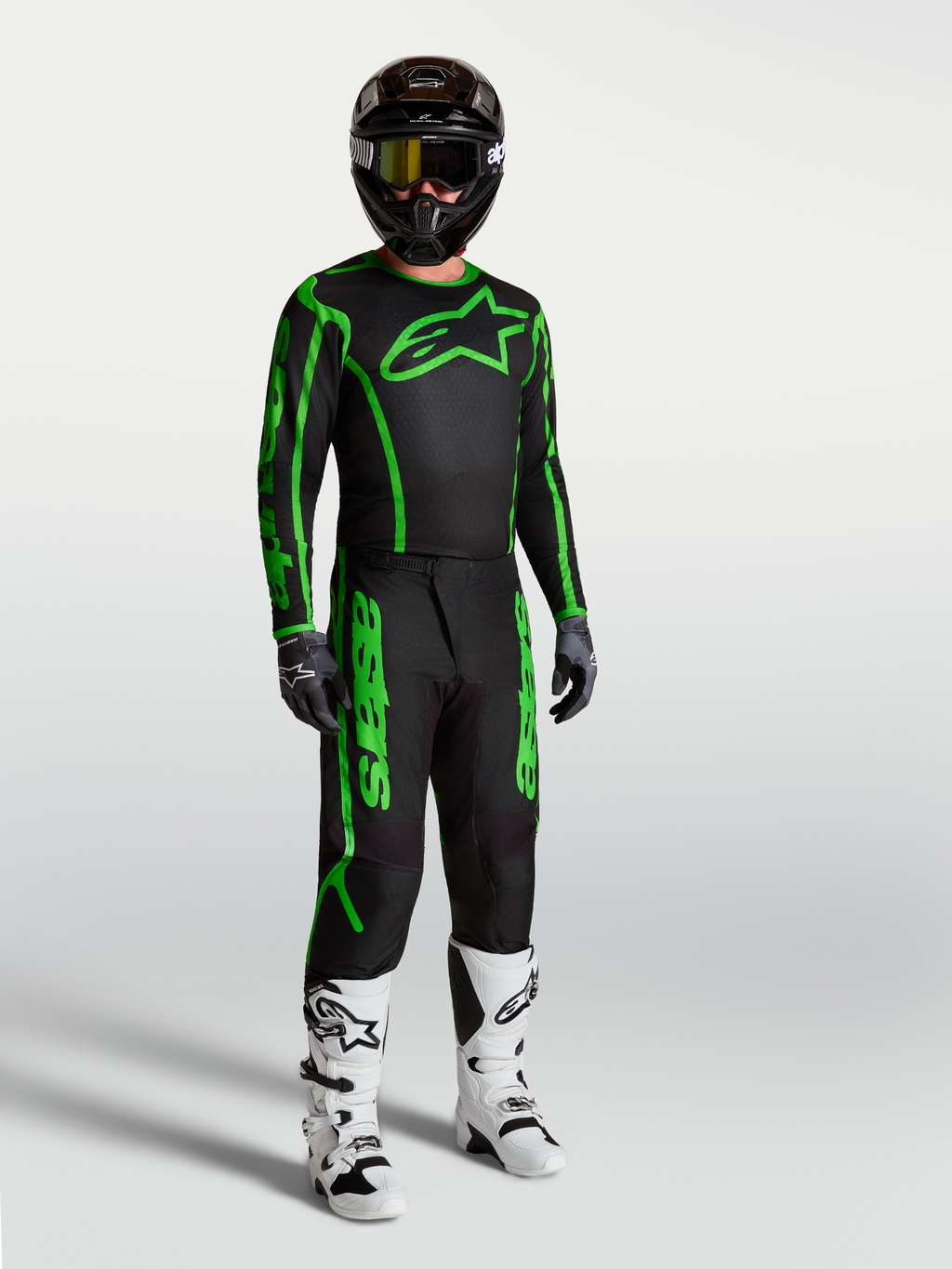 Alpinestars Fluid Apex V2 jersey, heren-motocrosskleding, zwart en fluogroen, met bijpassende broek en motorlaarzen.