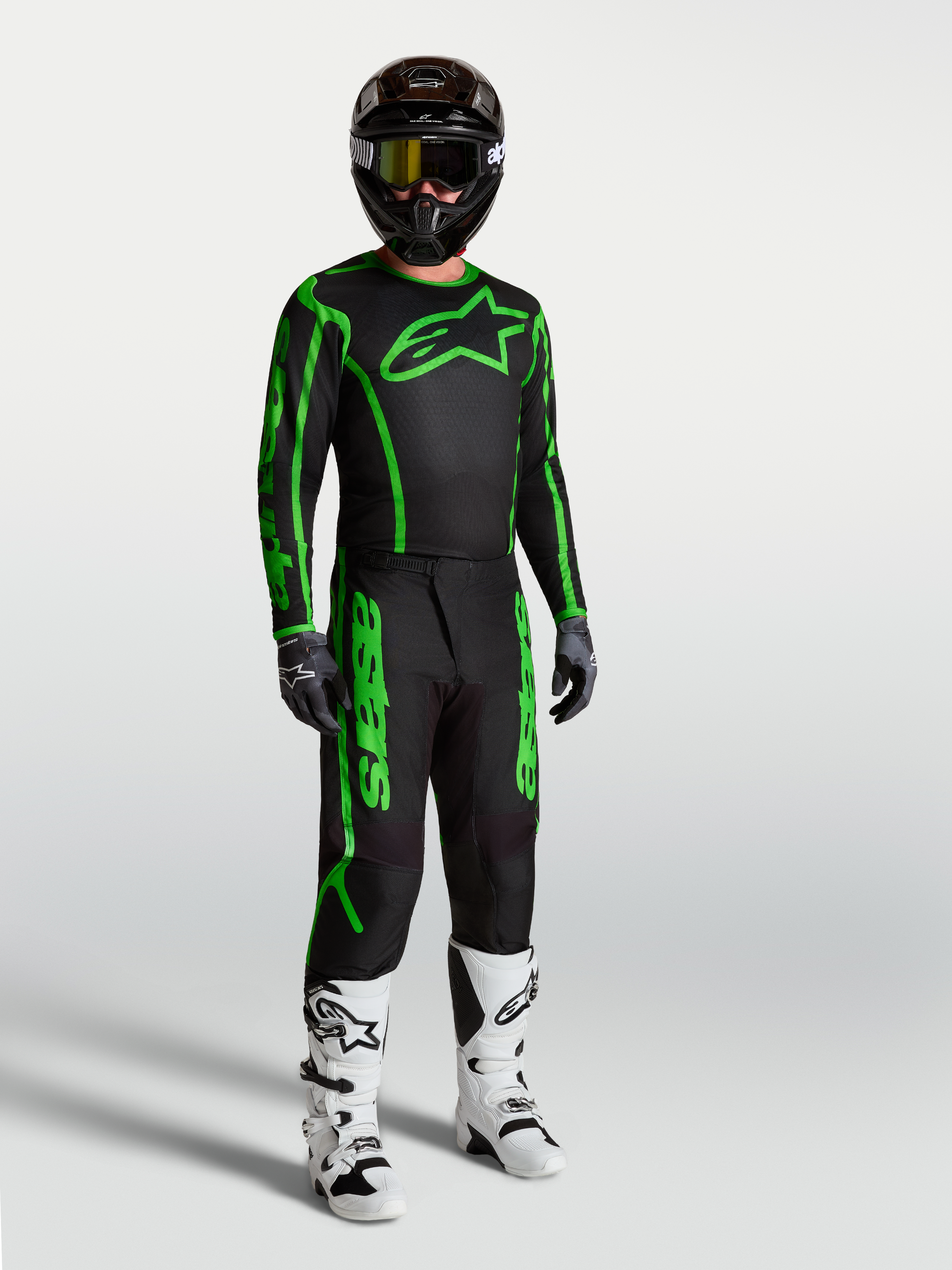 Alpinestars Fluid Apex V2 jersey, heren-motocrosskleding, zwart en fluogroen, met bijpassende broek en motorlaarzen.