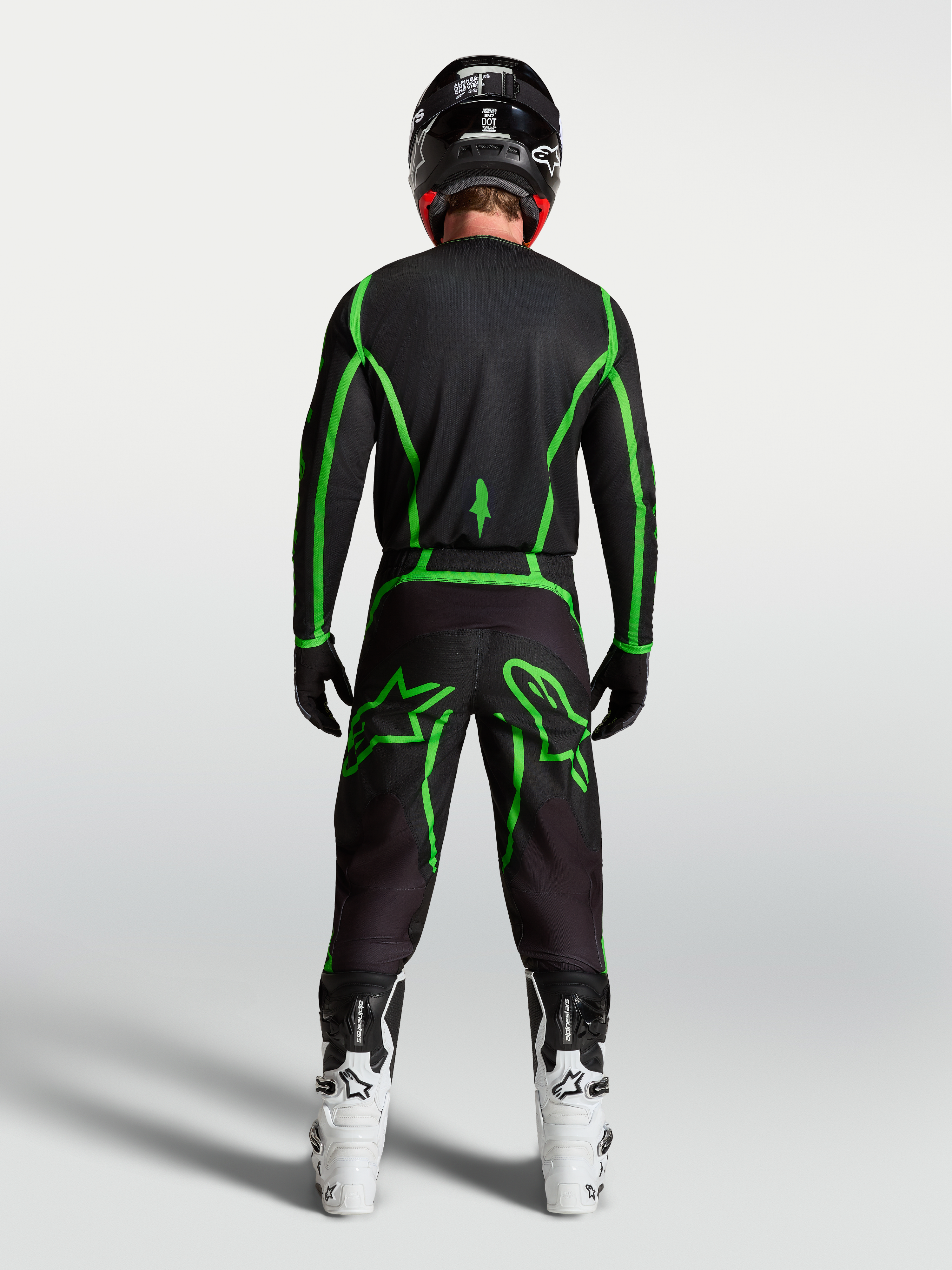 Alpinestars Fluid Apex V2 Pants, Black and Green Fluo motocross gear shown from behind on a rider with white boots.