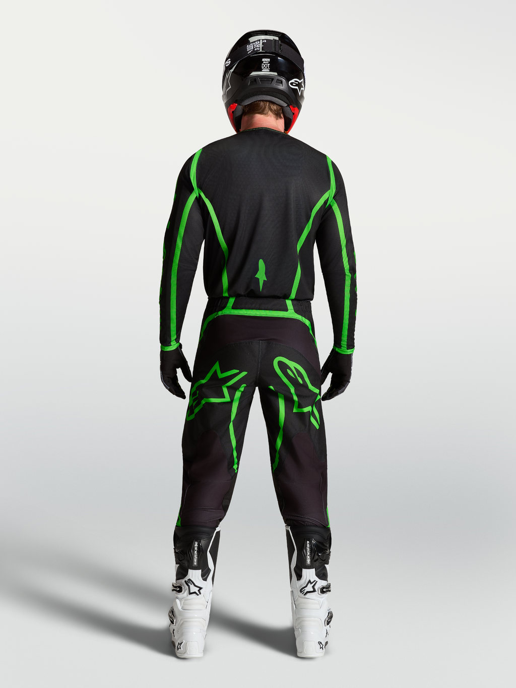 Alpinestars Fluid Apex V2 jersey, motocross jersey voor off-road rijden, zwart en fluogroen, achteraanzicht op model met witte motorlaarzen.