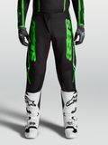 Pantalons Alpinestars Fluid Apex V2 2027, équipement de motocross pour homme, verts et noirs, avec genoux renforcés et bottes de moto blanches.