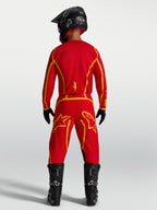 Alpinestars Fluid Apex V2 jersey, heren-motocrossjersey, rood en goud, achteraanzicht met motorlaarzen, vochtafvoerende stof.
