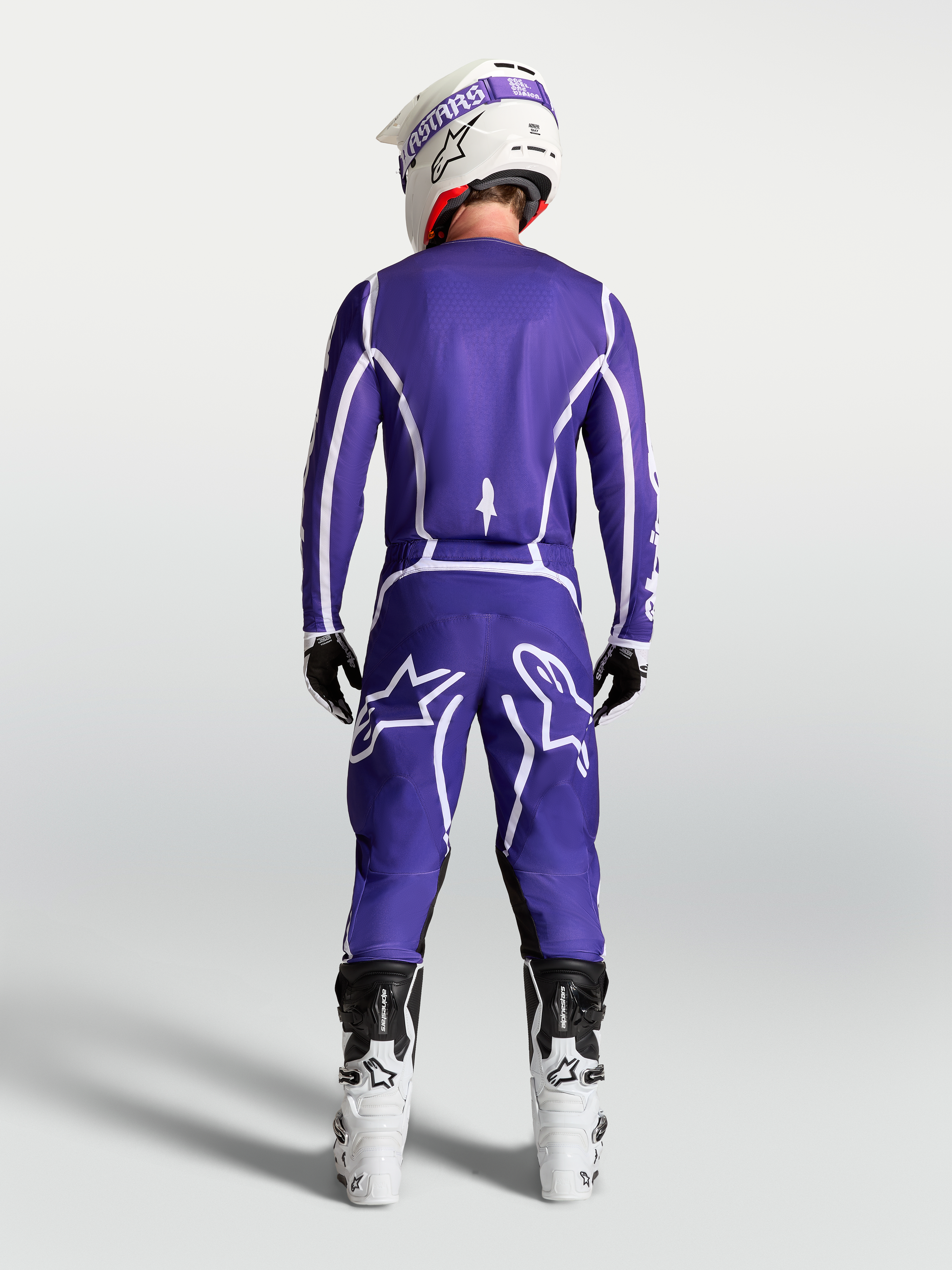 Maillot Alpinestars Fluid Apex V2, maillot de motocross tout-terrain bleu et blanc, vue de dos sur un pilote avec pantalon assorti et bottes blanches