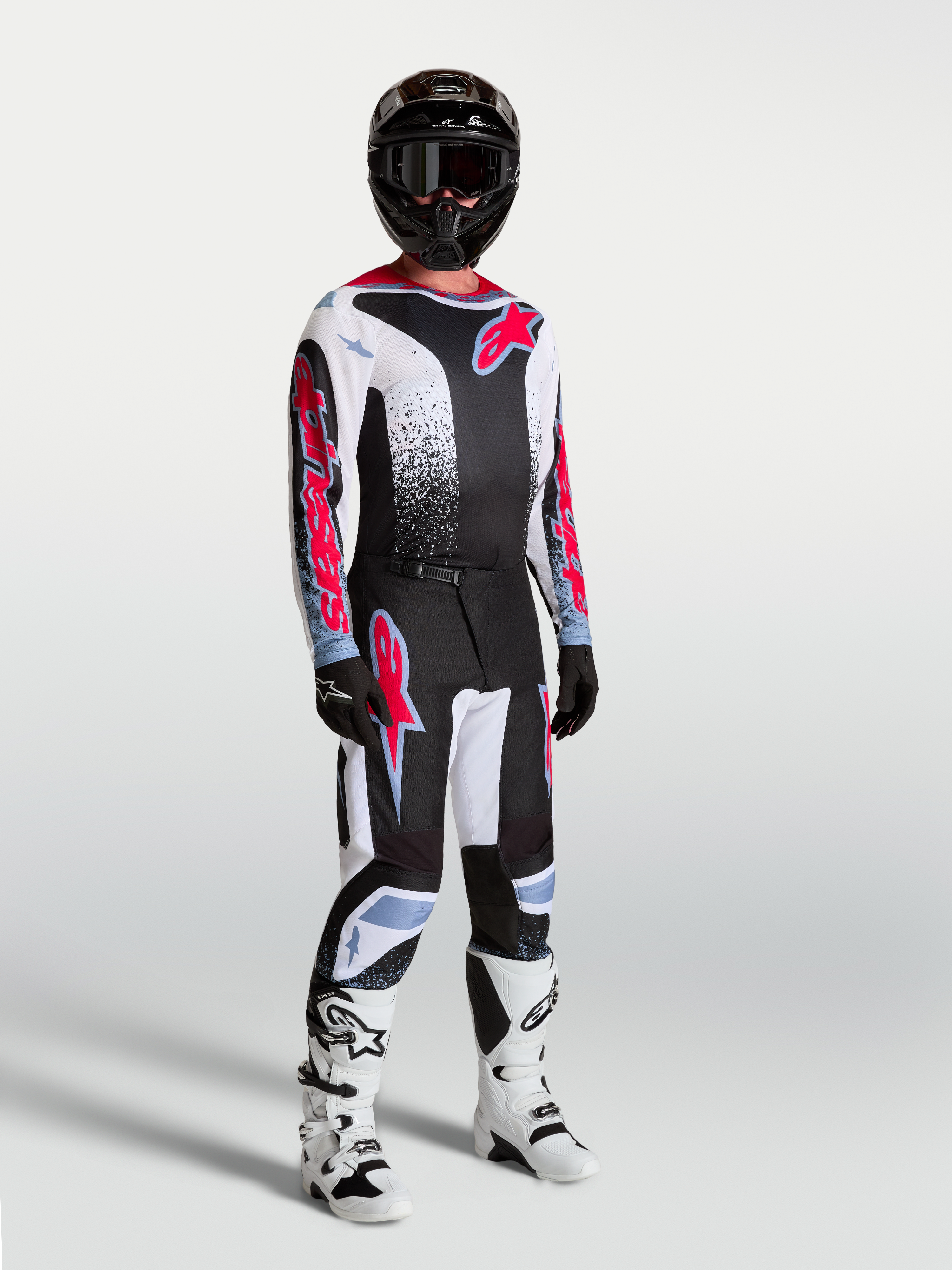 Alpinestars Fluid Drag jersey, ademende heren-motocrossjersey in zwart, wit en fluo rood, gedragen op model met volledige off-road uitrusting.