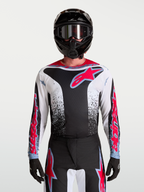 Alpinestars Fluid Drag jersey, heren-motorcrossjersey voor off-road en motocross, zwart en wit met fluo rode accenten en agressieve graphics, vooraanzicht gedragen door een model met helm.