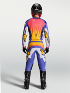 Alpinestars Fluid Drag broek en gear set, heren motorcrossoutfit in lila, blauw en goud, achteraanzicht op model.