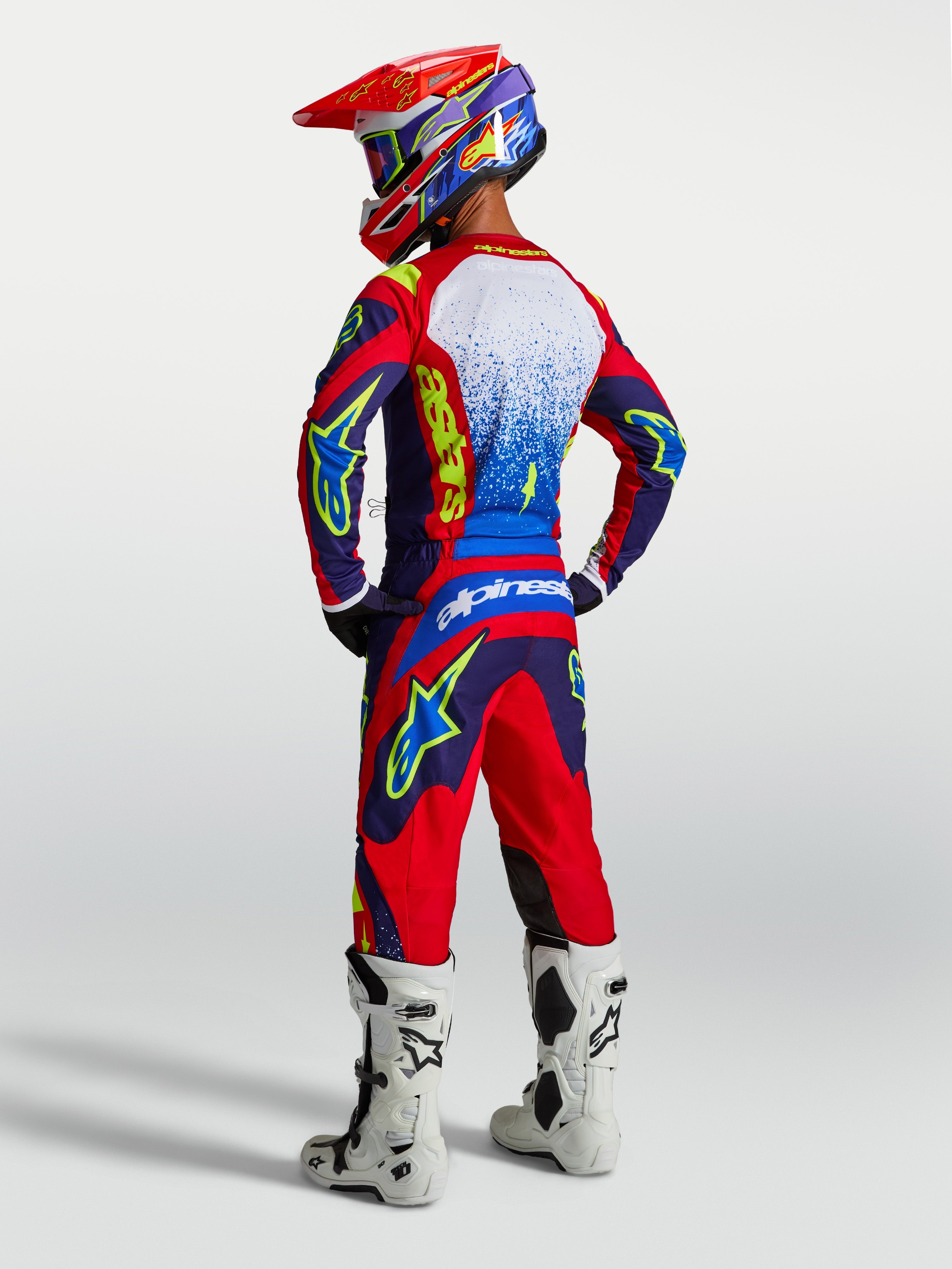 Alpinestars Fluid Drag jersey, blauw en rood motorcross-jersey, heren achteraanzicht met bijpassende gear en witte laarzen.