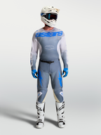 Alpinestars Racer Amber broek en jersey, heren motocrossuitrusting in grijs en UCLA blauw, met witte laarzen en helm, duurzame off-road race-uitrusting.
