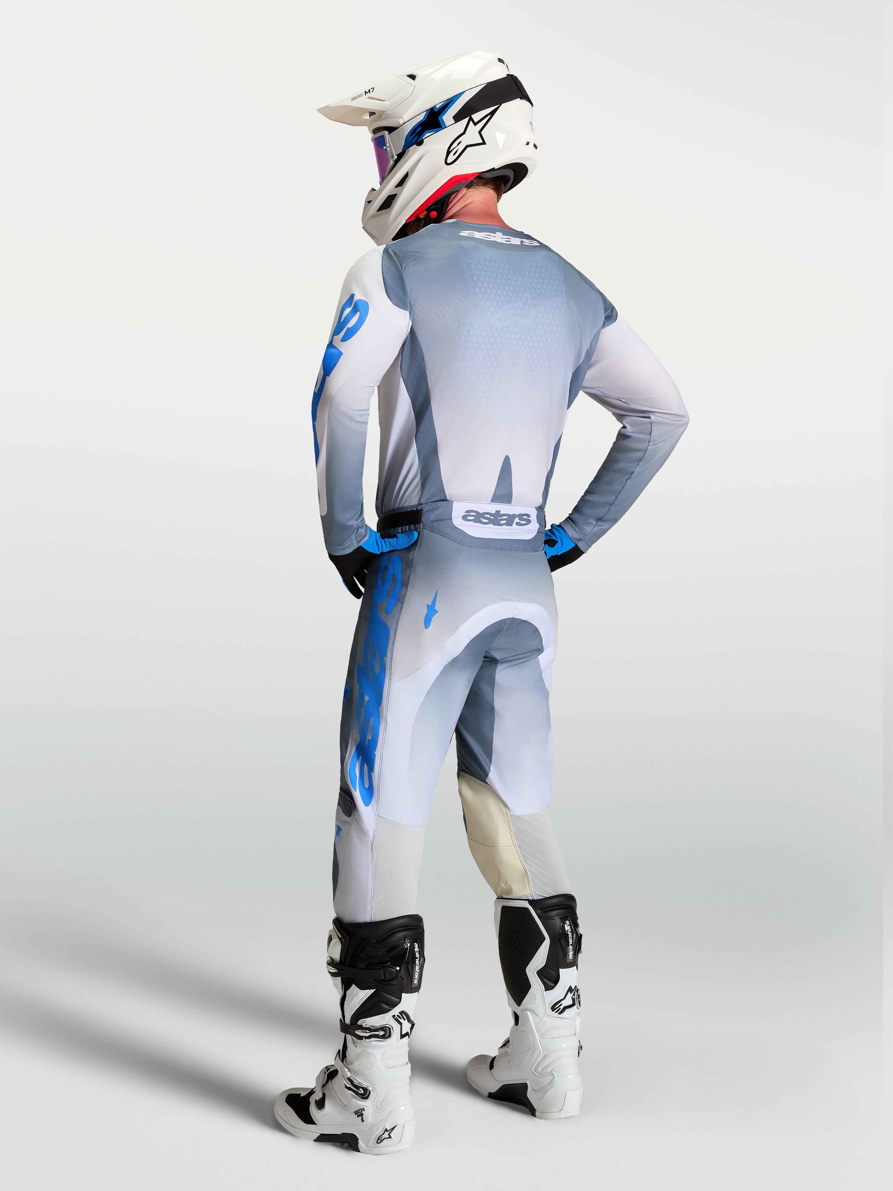 Alpinestars Racer Amber broek en uitrustingsset, grijze en blauwe motorcrosskleding, achteraanzicht op een rijder.