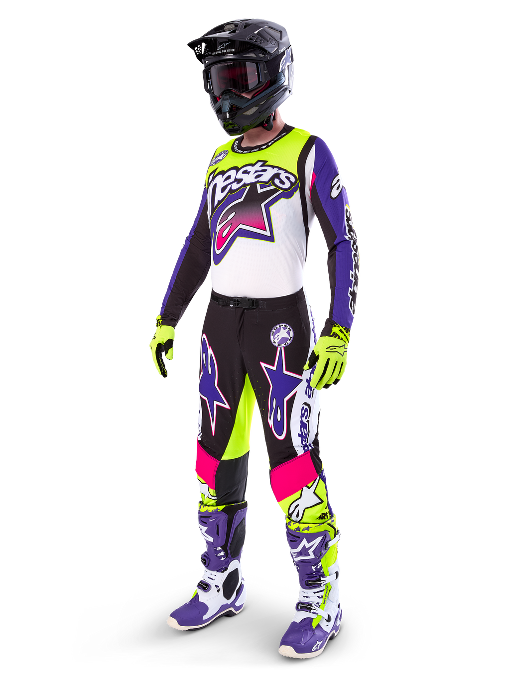 Motocross-Fahrer in Alpinestars Limited Edition Supertech Dirt Studios® Ausrüstung, Farbkombination in Weiß, Lila und Neongelb, schwarze Hose mit auffälligen lila und pinkfarbenen Stern-Logos, neongelbe Handschuhe, lila-weiße Rennstiefel, schwarzer Helm, komplette professionelle Rennausrüstung für Offroad-Performance
