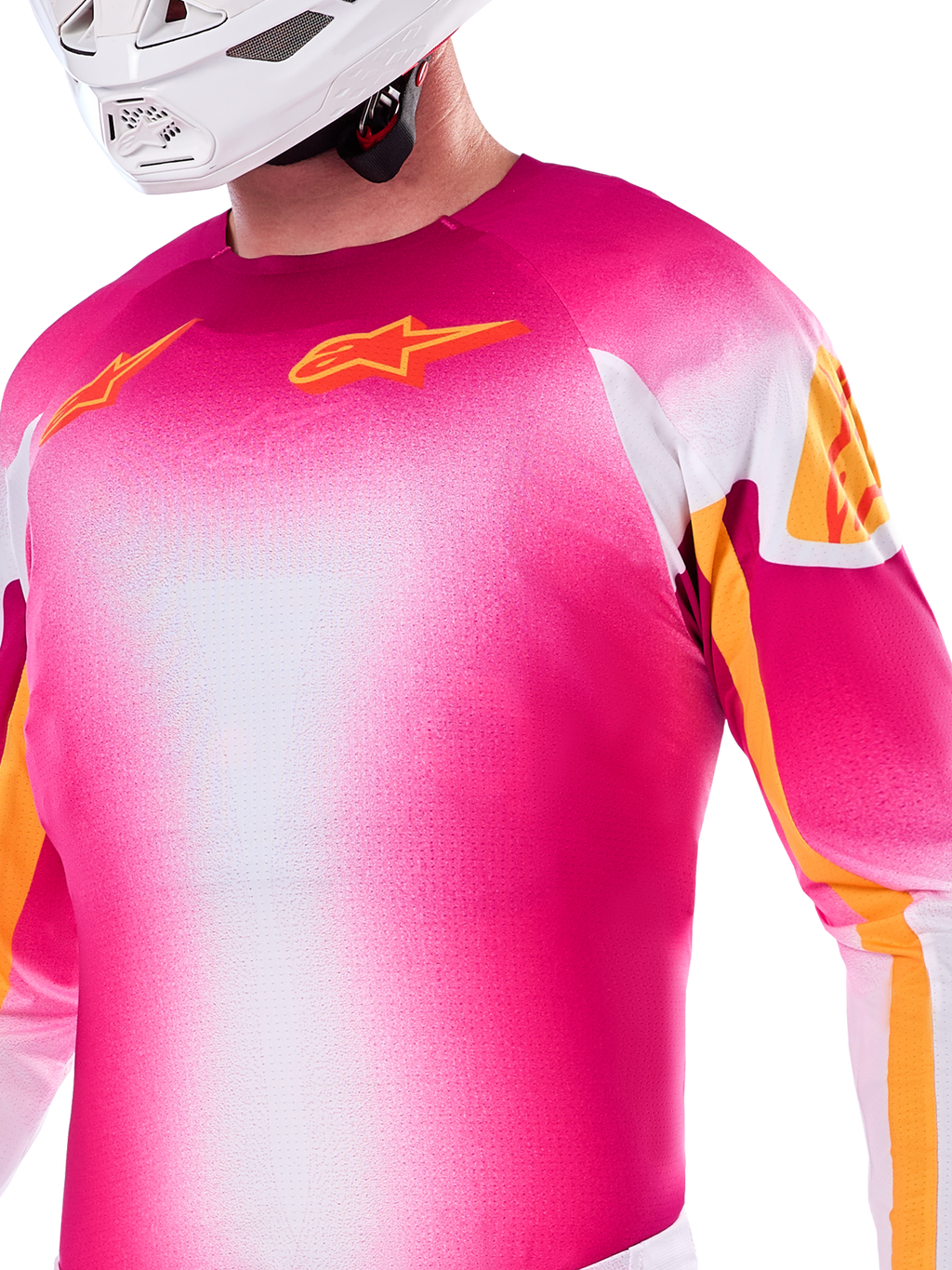 Alpinestars Limited Edition Supertech AFD MIG Jersey, Motocross-Jersey mit Farbverlauf in Pink Fluo und Weiß, mit orangefarbenen Astars-Logos und Ärmelakzenten, getragen von einem Fahrer mit weißem Helm, athletische Racing-Passform.