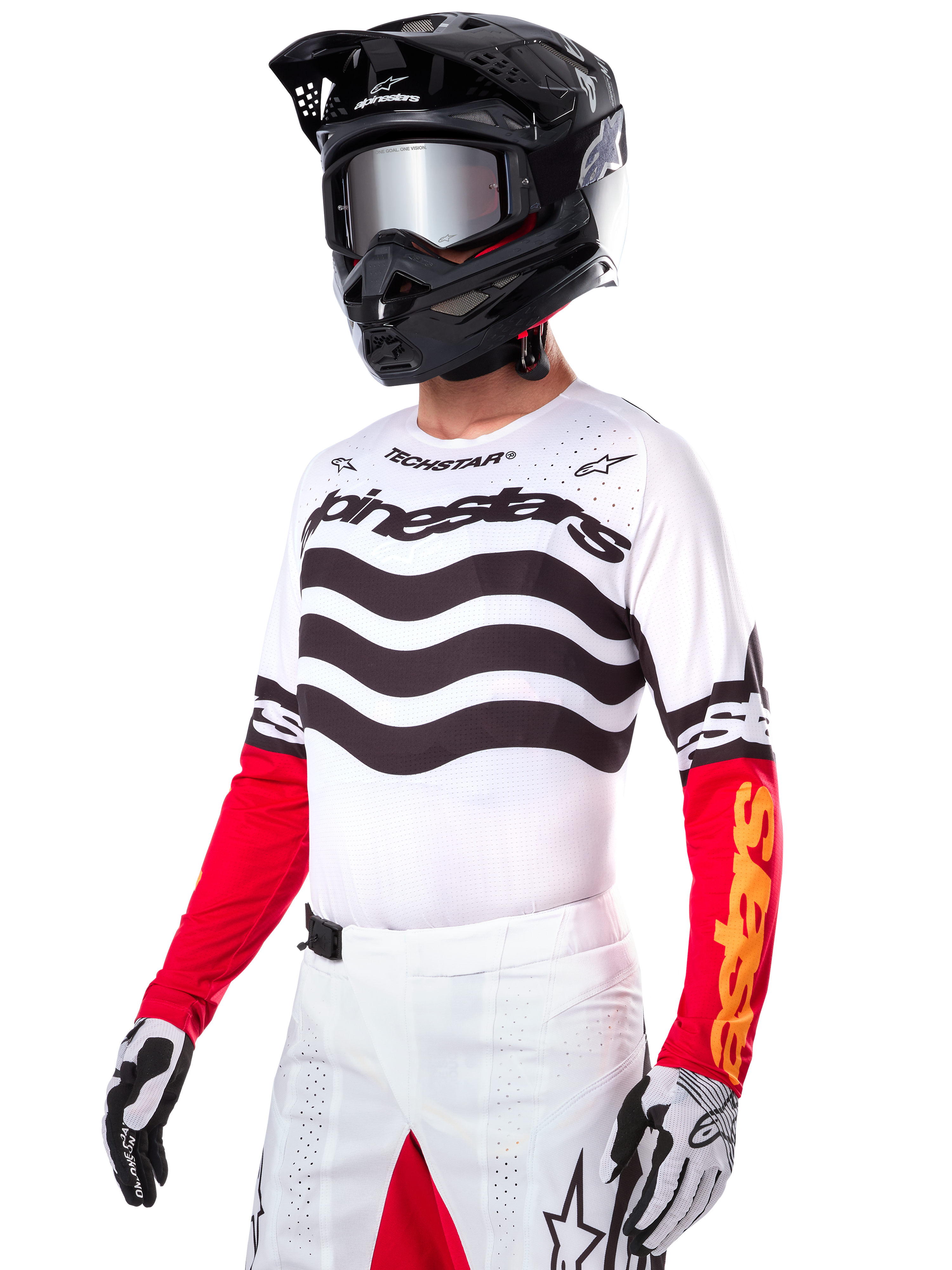 Motocross-Fahrer im Alpinestars Limited Edition Techstar Deep Jersey, weißes Trikot mit schwarzen Wellenstreifen und roten Unterärmeln, kombiniert mit schwarzem Helm, verspiegelter Brille, weiß-schwarzen Handschuhen und weißer Rennsport-Hose, Performance-Motocross-Outfit.