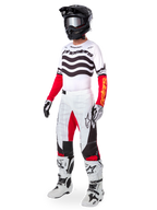 Motocross-Fahrer in kompletter Rennausrüstung, Limited Edition Techstar Deep Jersey mit weiß-schwarzen Wellenstreifen und roten Ärmeln, passender weiß-roter Hose, schwarzem Helm und weiß-schwarzen Stiefeln, koordiniertes Outfit für den Offroad-Rennsport