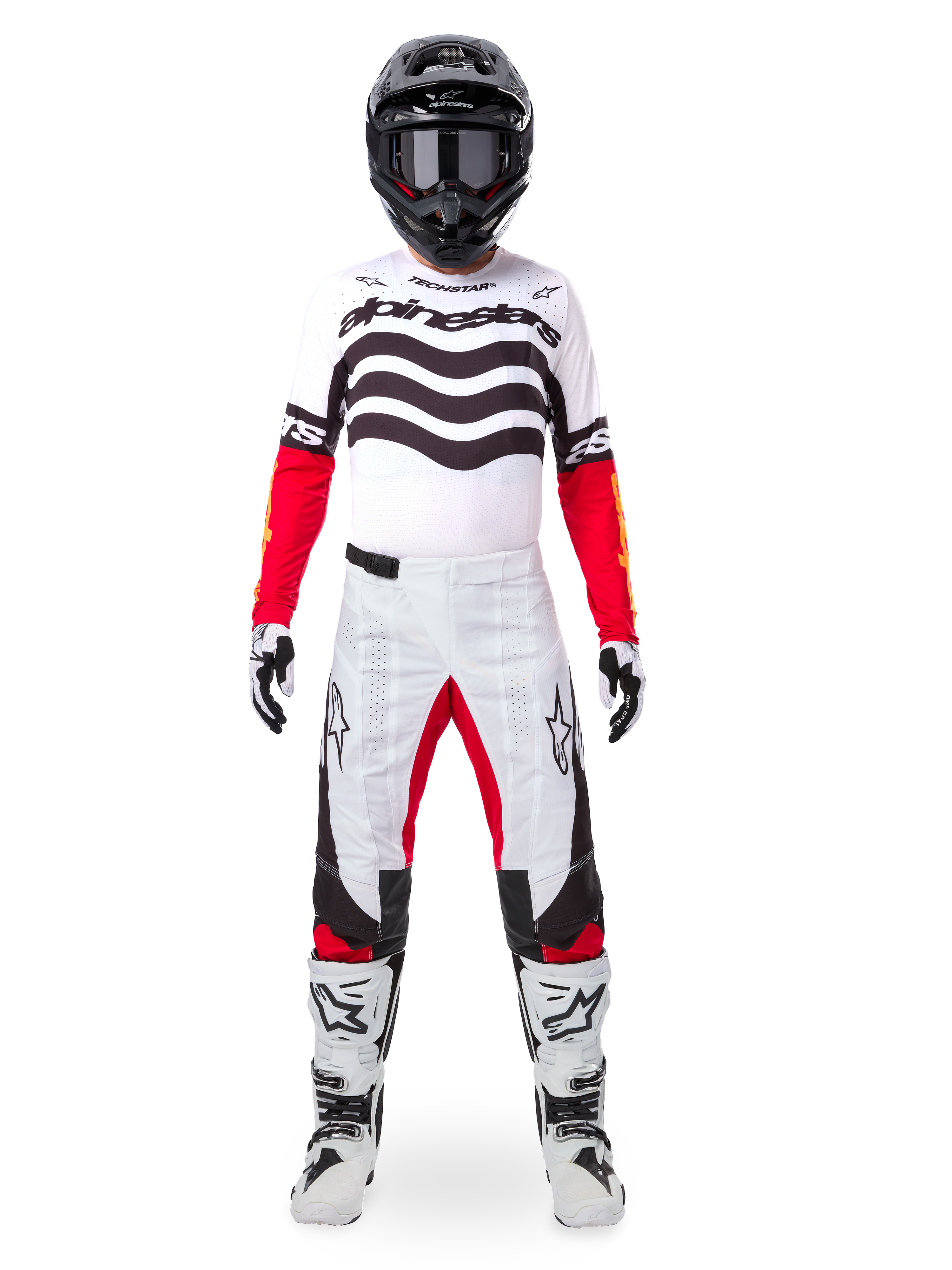 Motocross-Fahrer im Alpinestars Limited Edition Techstar Deep Trikot in Weiß, Schwarz und Rot mit wellenförmigen Grafiken auf der Brust, kombiniert mit einer passenden weiß-roten Hose, einem schwarzen Helm und weißen Rennstiefeln, komplette professionelle Offroad-Ausrüstung.