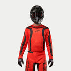 Motocrossrijder in Alpinestars 2024 Fluid Lurv Jersey, Hot Orange en zwart, bijpassende motorcrossbroek, zwarte helm met crossbril en zwarte handschoenen, gecoördineerde uitrusting voor off-road racing