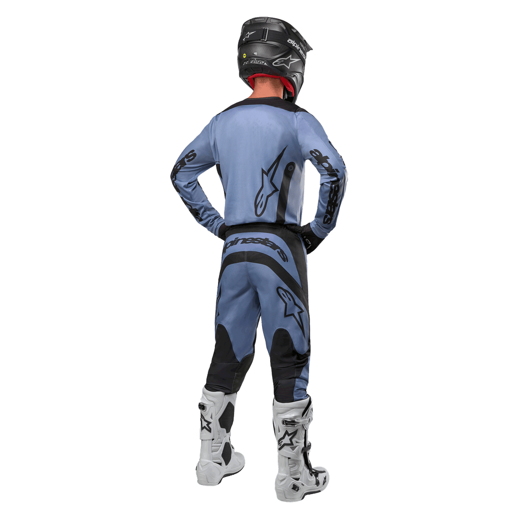 Motocross-Fahrer von hinten, Alpinestars 2024 Fluid Lurv Trikot und passende Hose in Hellblau und Schwarz, schwarzes Branding auf dem Rücken und den Ärmeln, schwarzer Helm und weiße Stiefel.