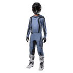 Motocross-Fahrer in kompletter Rennausrüstung, Alpinestars 2024 Fluid Lurv Trikot in Hellblau und Schwarz, passende hellblaue Hose mit schwarzen Einsätzen, weiß-schwarze Stiefel, schwarze Handschuhe, schwarzer Helm mit Brille, abgestimmtes Outfit für den Offroad-Rennsport