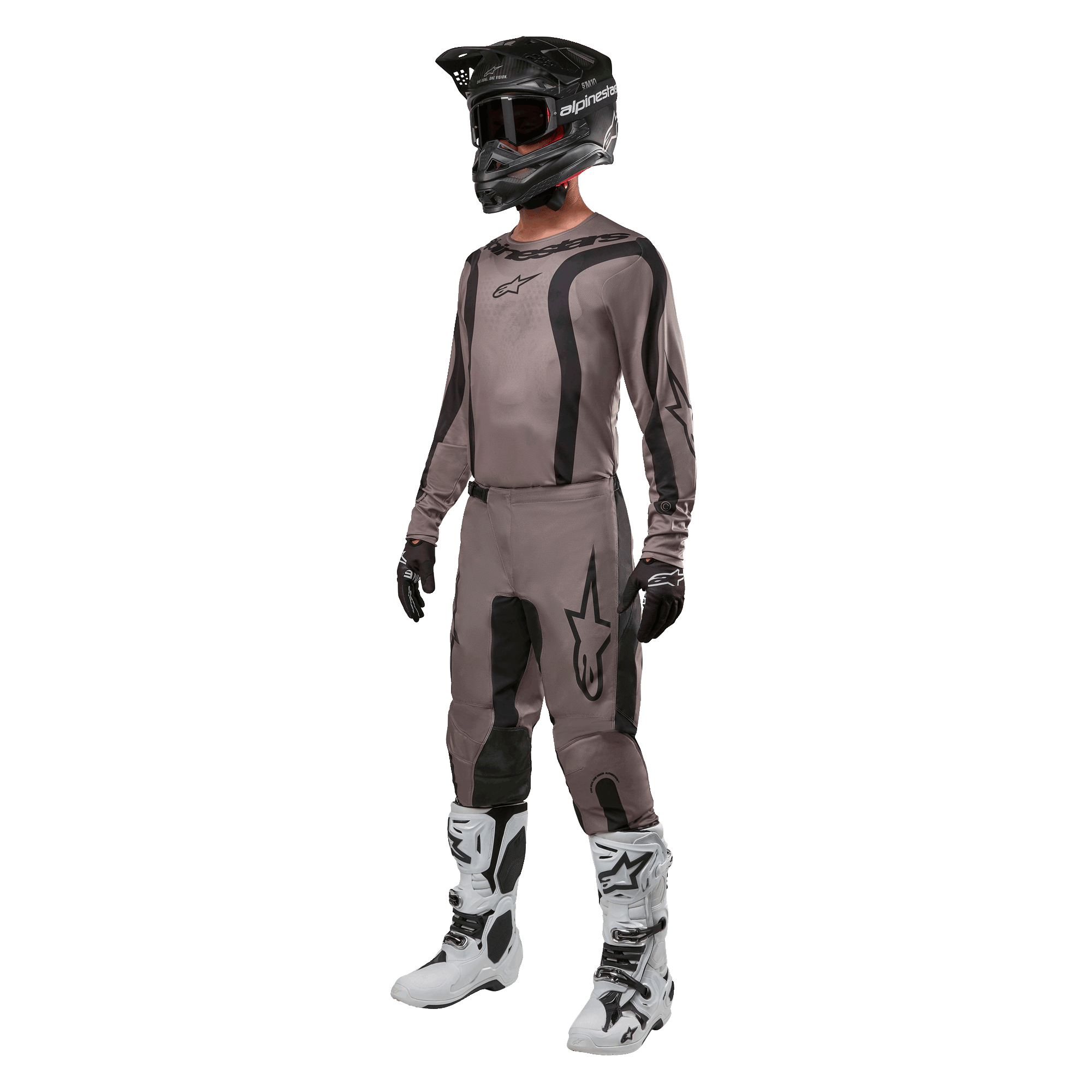 Motocross-Fahrer in kompletter Rennausrüstung mit dem Alpinestars 2024 Fluid Lurv Jersey in Mud Black, kombiniert mit der passenden Hose, schwarzem Helm mit Brille, weiß-schwarzen Stiefeln und schwarzen Handschuhen, koordiniertes Outfit für den Offroad-Rennsport