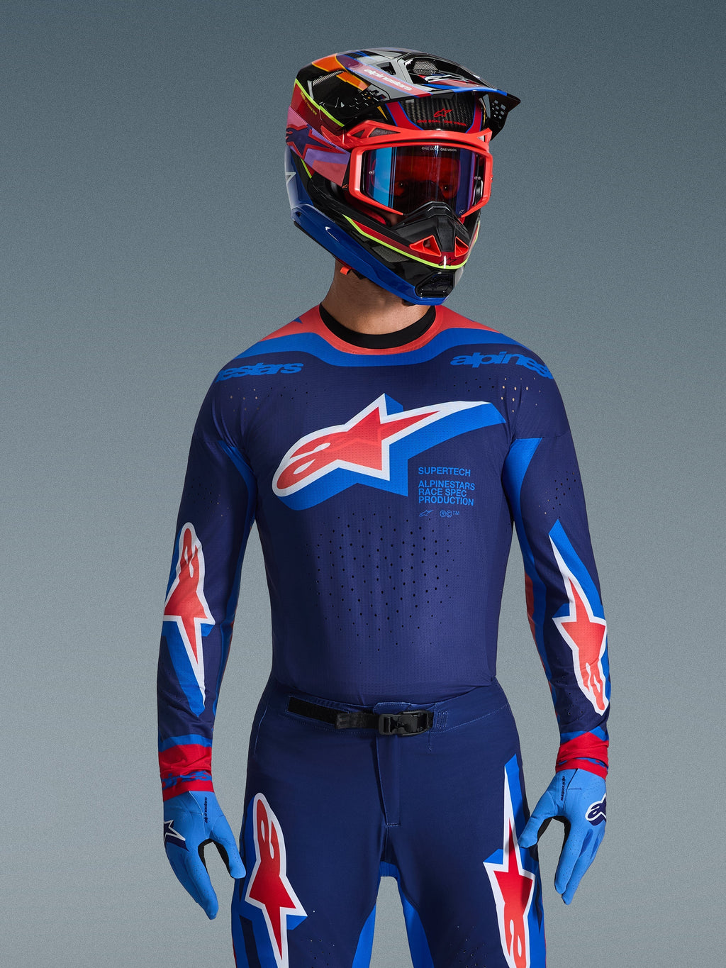 Alpinestars 2026 Supertech Vista Jersey, Motocross Jersey, Dark Navy Hot Coral and Cobalt, worn with matching motocross pants and helmet, featuring large star logo on chest and race spec branding, athletic fit with ventilated mesh panels for elite racing performance