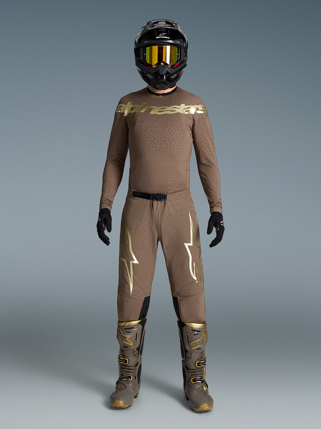 Beige Supertech Air Gold Beperkte Oplage Kledingset met metallic gouden logo's, bijpassende motorlaarzen en helm.