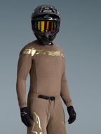 Tenue complète Alpinestars Supertech Air Gold Édition Limitée, ensemble de motocross marron et doré avec ventilations laser, porté par un pilote.