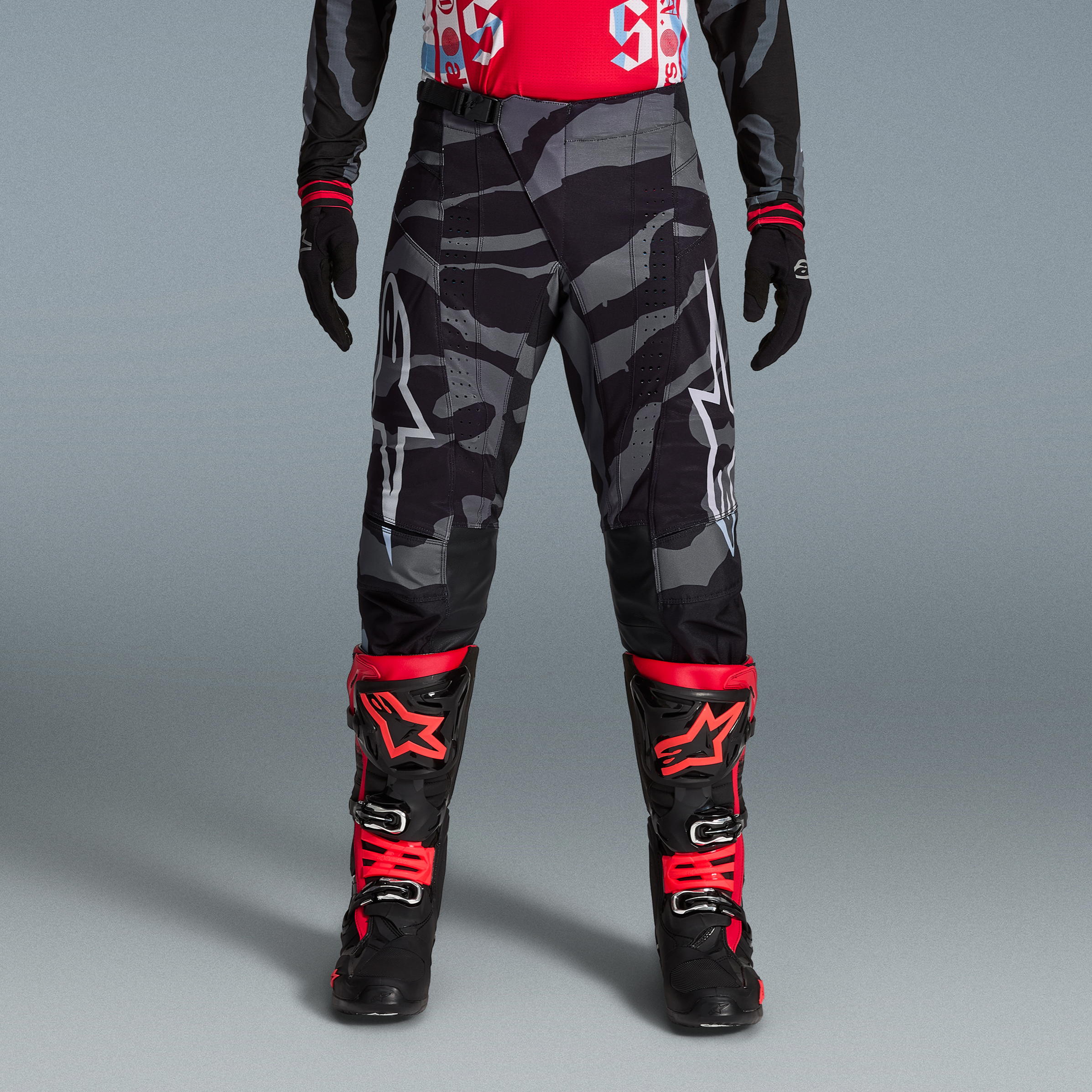 Techstar Beast Coast crossbroek, grijs-zwart camouflage met wit logo, gecombineerd met rode en zwarte motorlaarzen.